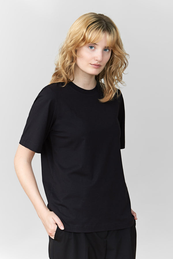 A woman wearing a black regular T-shirt with a classic crewneck and black trousers.