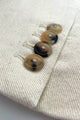 Closeup of  of a horn buttoned, cream-hued jacket sleeve