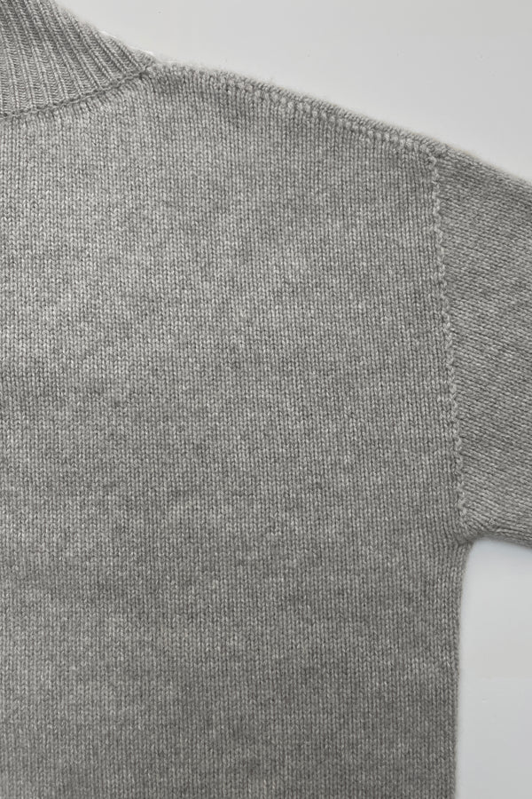 Detail of shoulder seem on a v-neck cashmere sweater in light grey photographed flat.