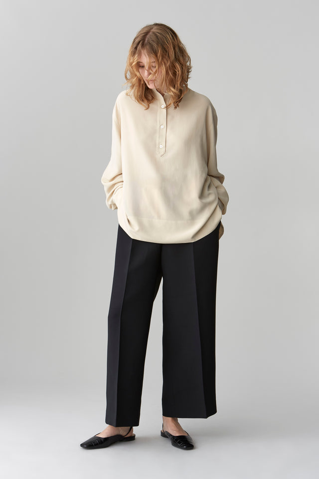 Model wearing HELEN oversized silk blouse in cream, featuring a standing collar and mid-length button placket.