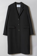 A black, single-breasted coat made of a mid-weight fabric with notch lapels, flap- and breast pockets, and black horn buttons showed flat from the front.